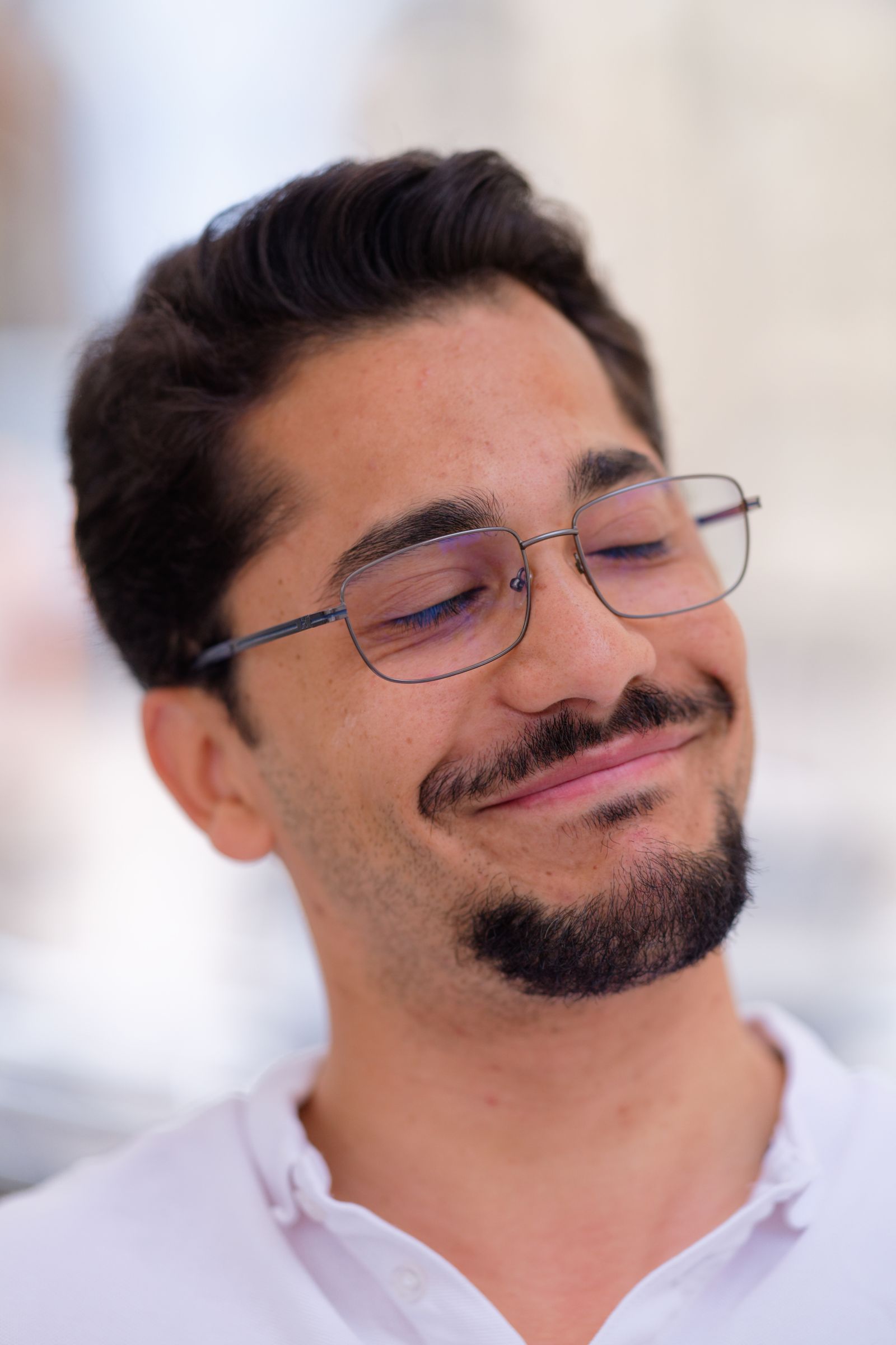 Gros plan sur un homme souriant à lunettes, détendu et serein, en extérieur