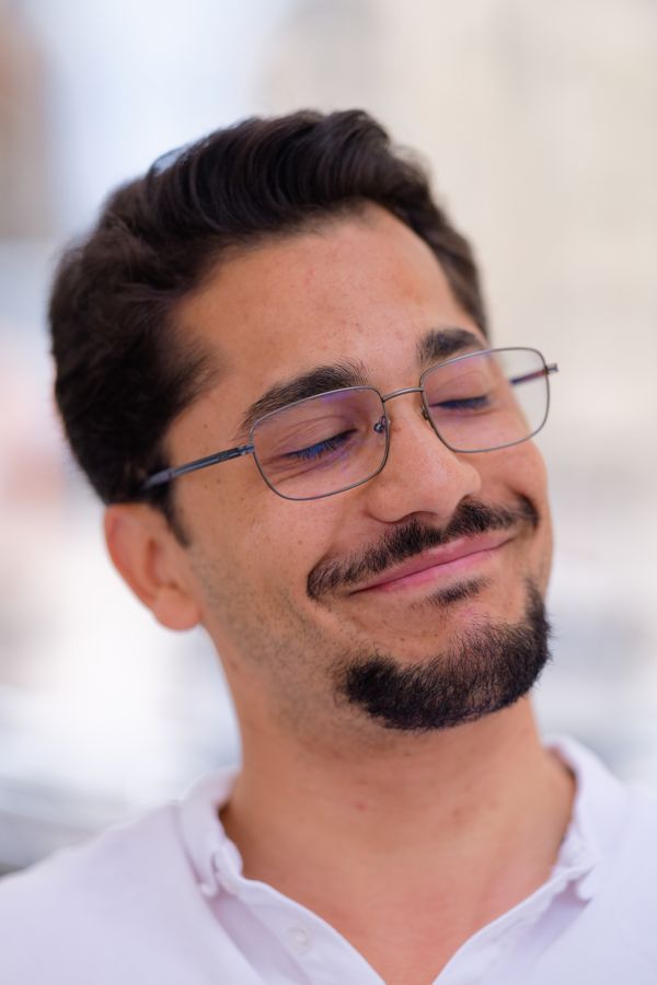 Gros plan sur un homme souriant à lunettes, détendu et serein, en extérieur