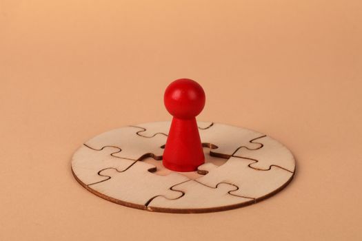 A red pawn stands on a wooden circular puzzle, symbolizing strategy and problem-solving.