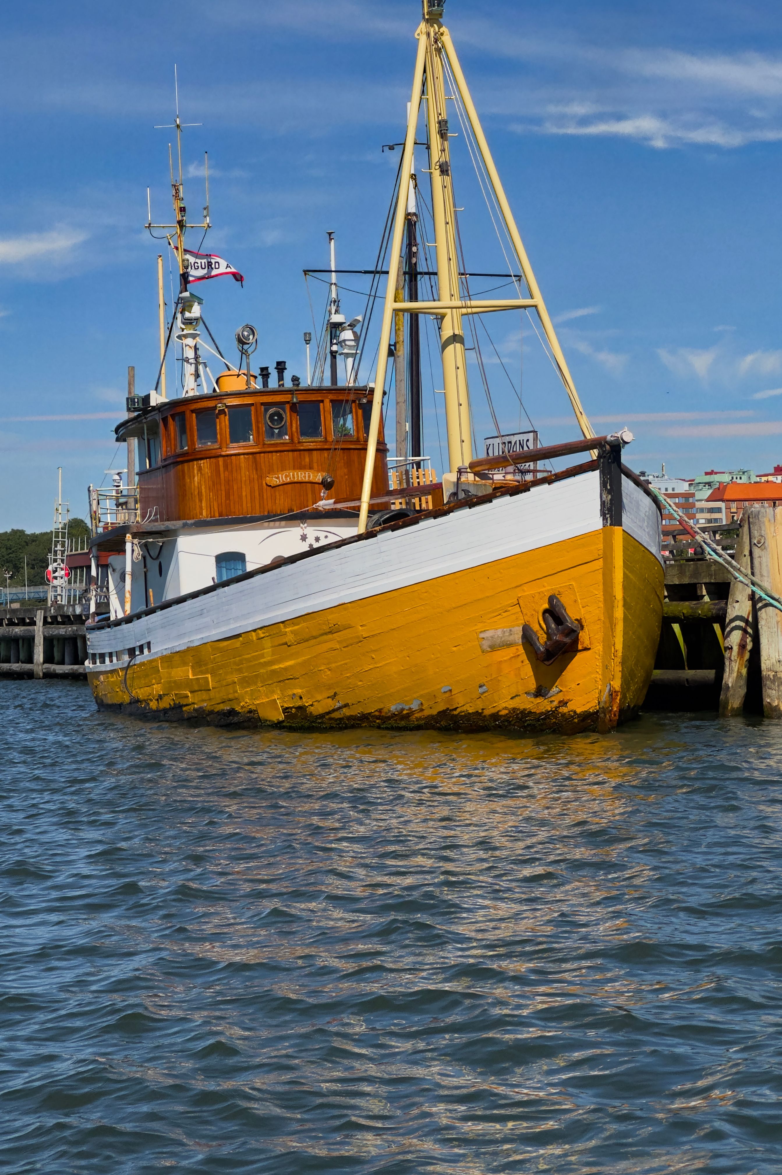 Colorful boat moored at a dock under a clear sky in Göteborg, showcasing nautical charm.