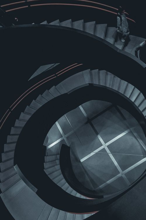 Free From above staircase flights with spiral stairs of dark gray color located in modern residential multi storey building Stock Photo