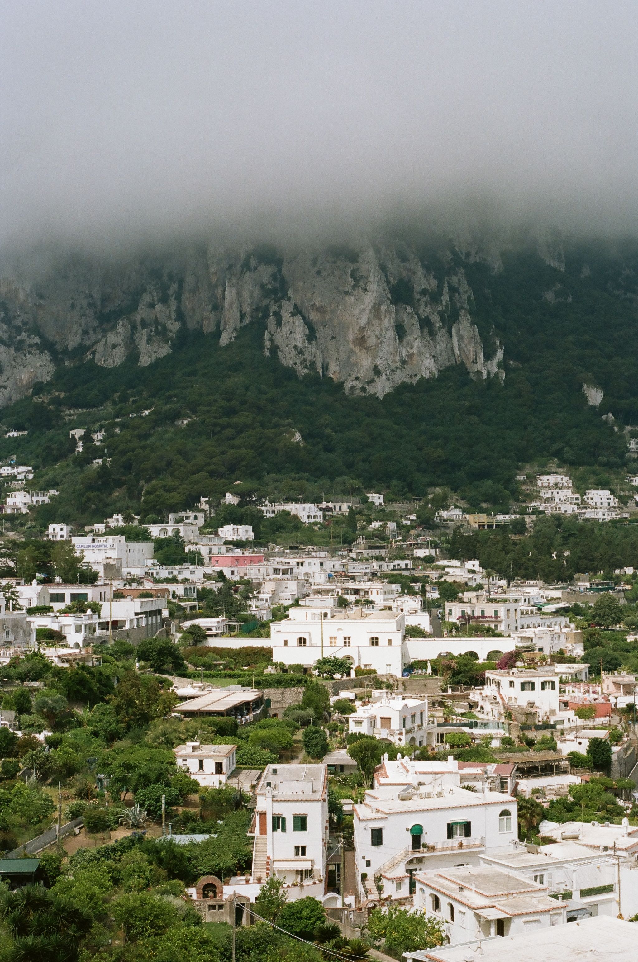 A scenic view of Capri, Italy under dense cloud cover during a summer day.