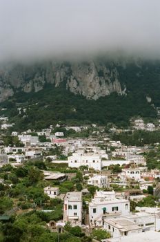 A scenic view of Capri, Italy under dense cloud cover during a summer day.