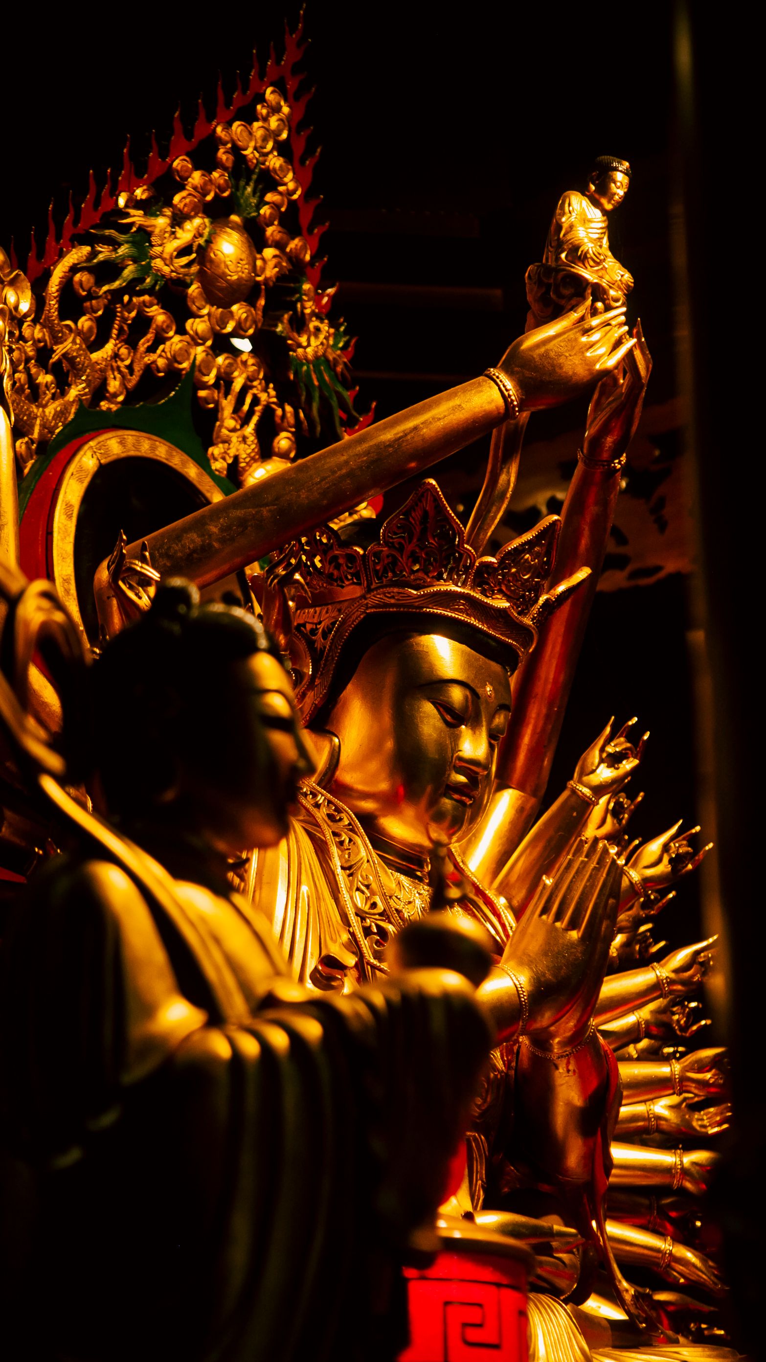 Intricate golden Buddhist statues captured with warm lighting, showcasing traditional artistry.