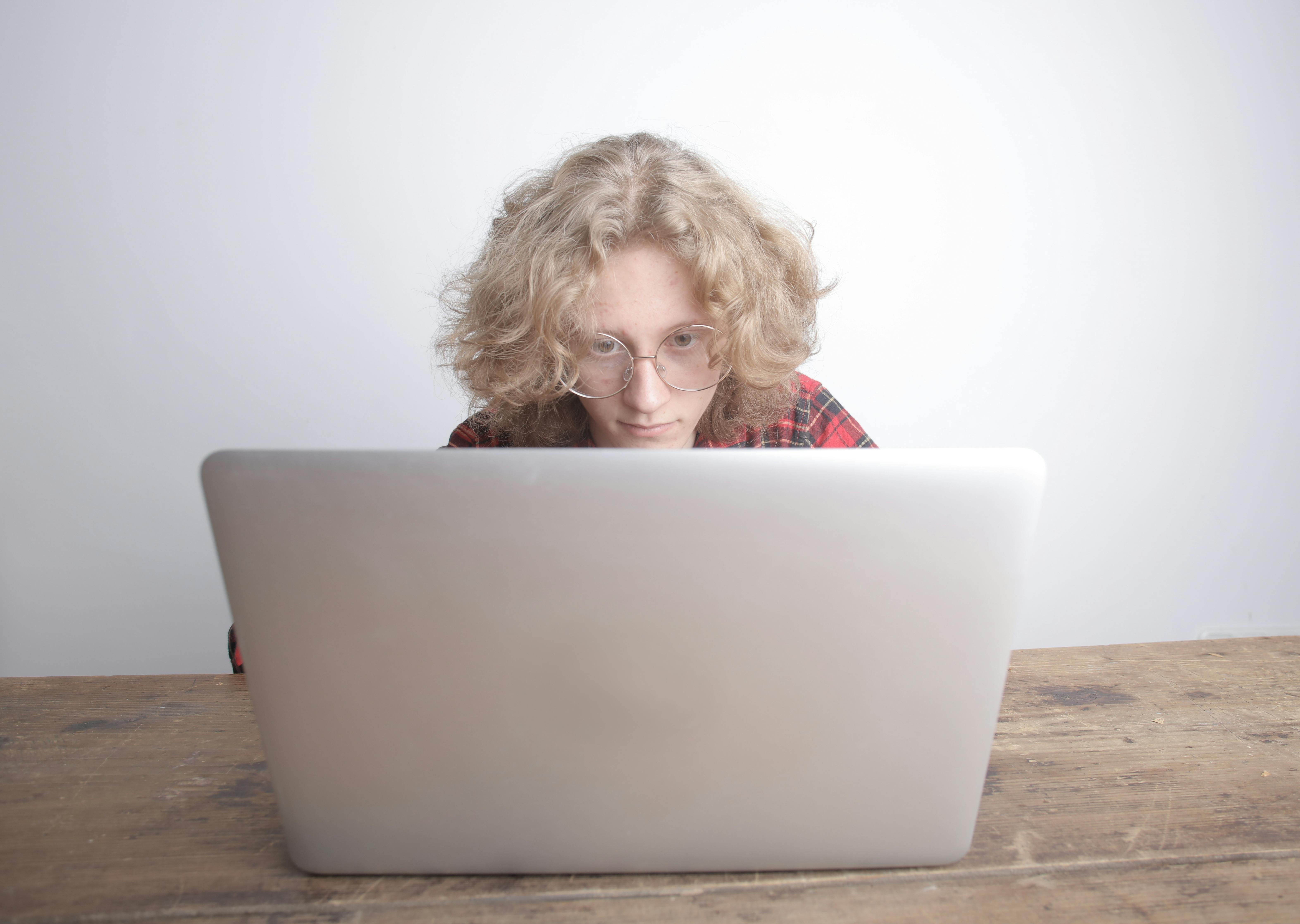 man in red plaid shirt wearing eyeglasses using laptop