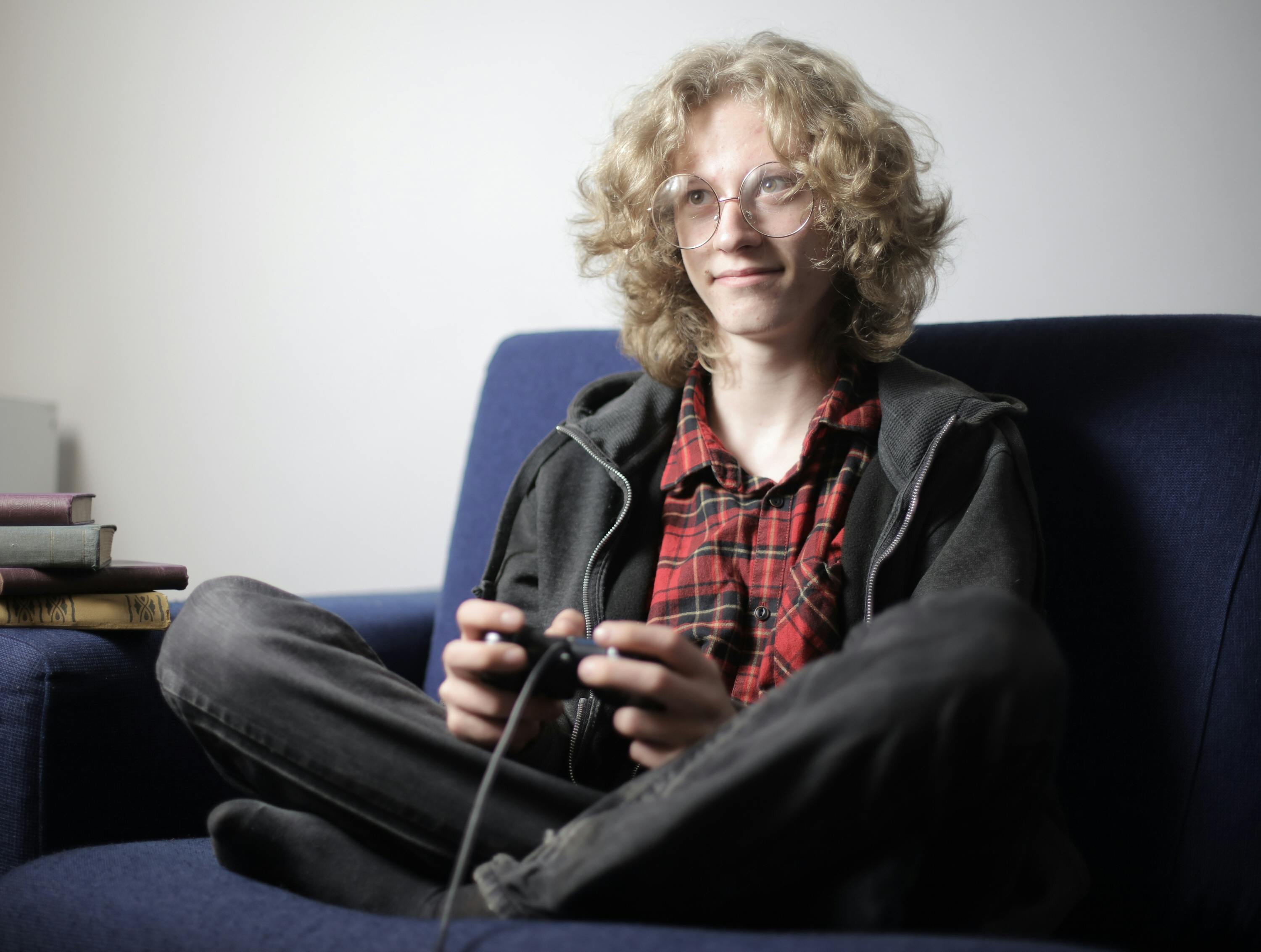 smiling teenager playing video game on sofa