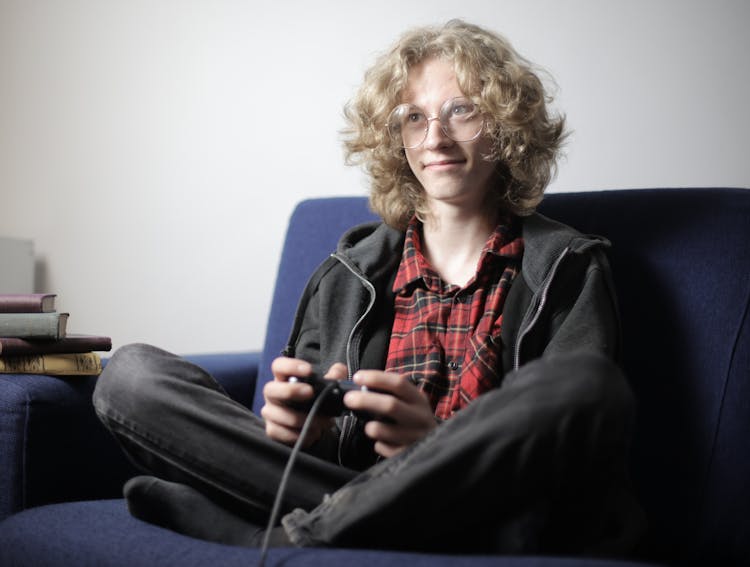 Smiling Teenager Playing Video Game On Sofa