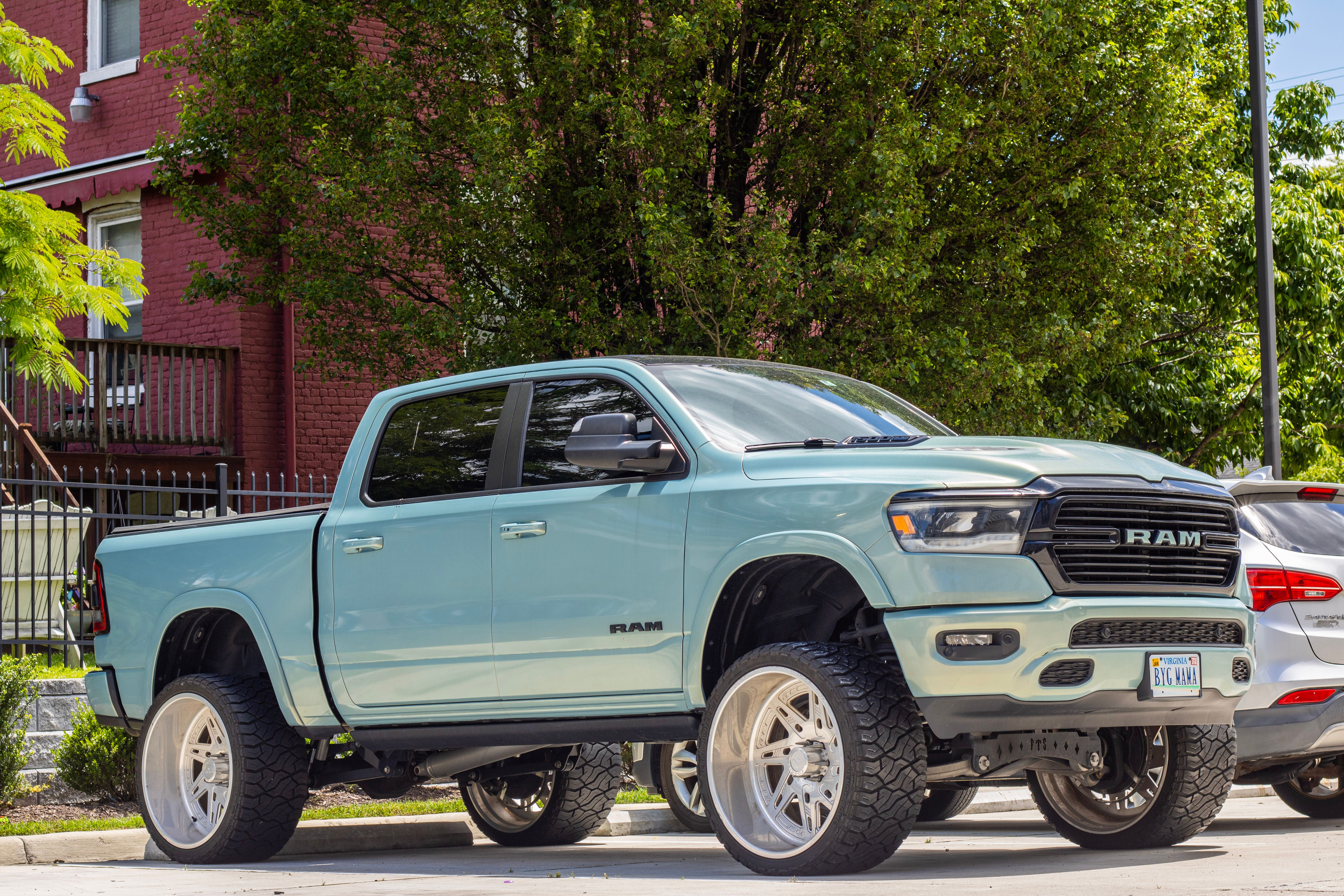 Customized RAM truck with large tires parked in a city neighborhood, showcasing urban style and automotive design.