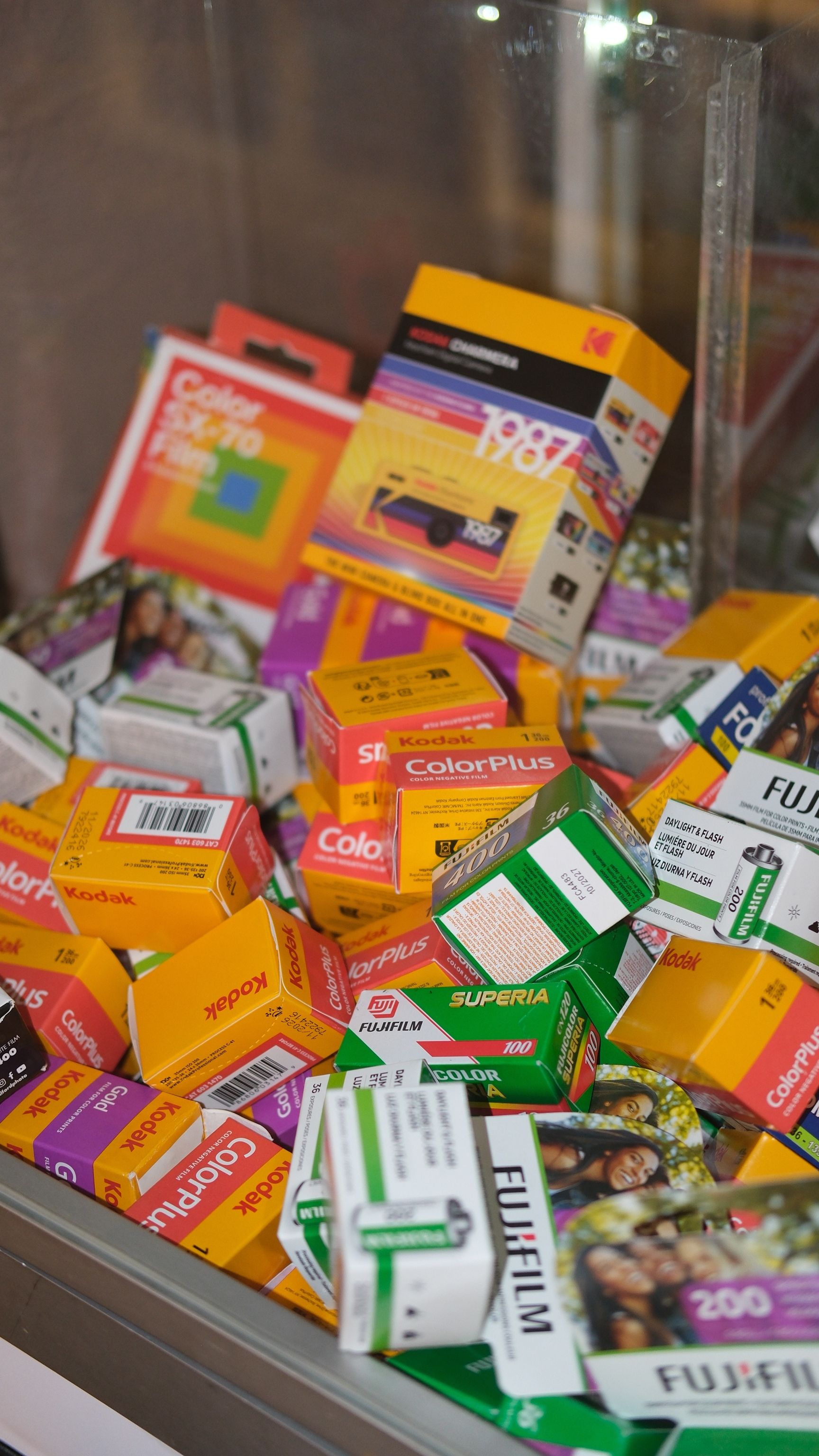 Assorted Kodak and Fujifilm boxes showcasing retro film in a glass display.