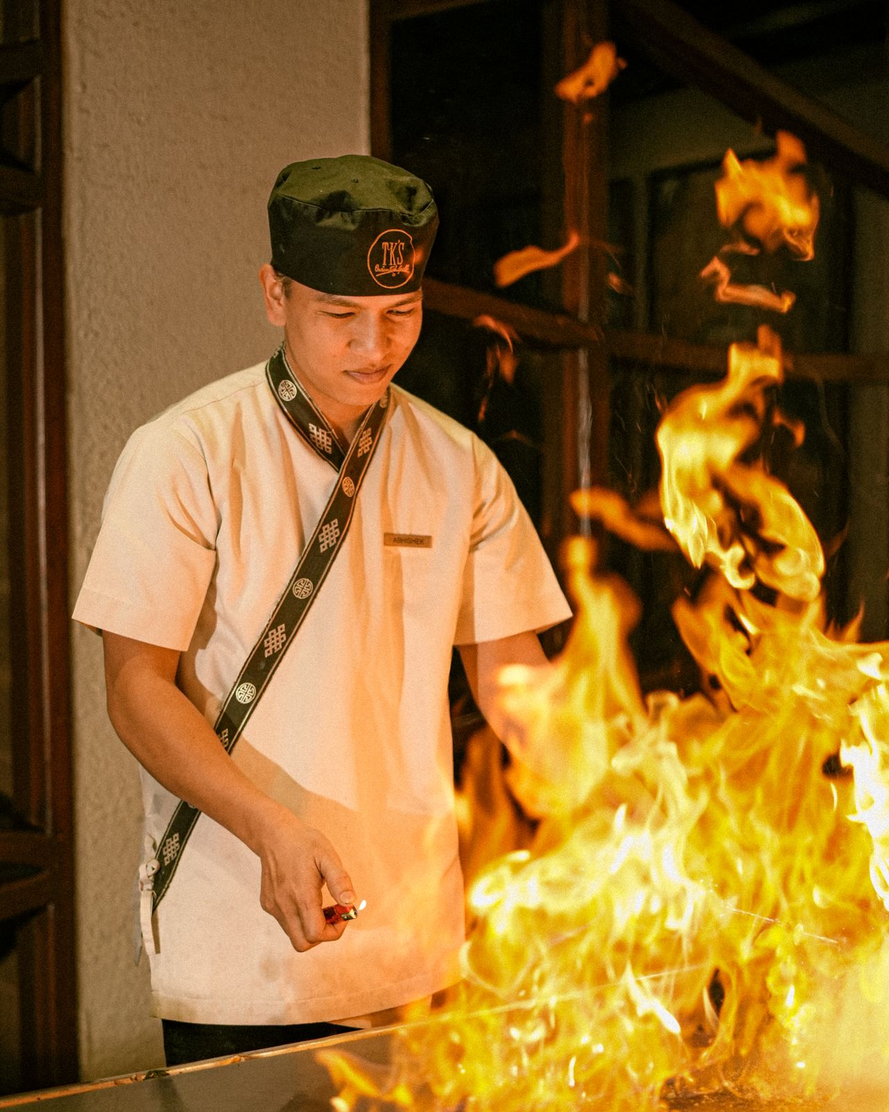 A hibachi chef cooking with flames on a teppanyaki grill