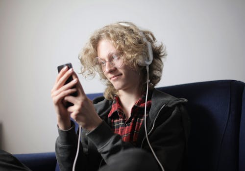 Smiling teenager with headphones using smartphone