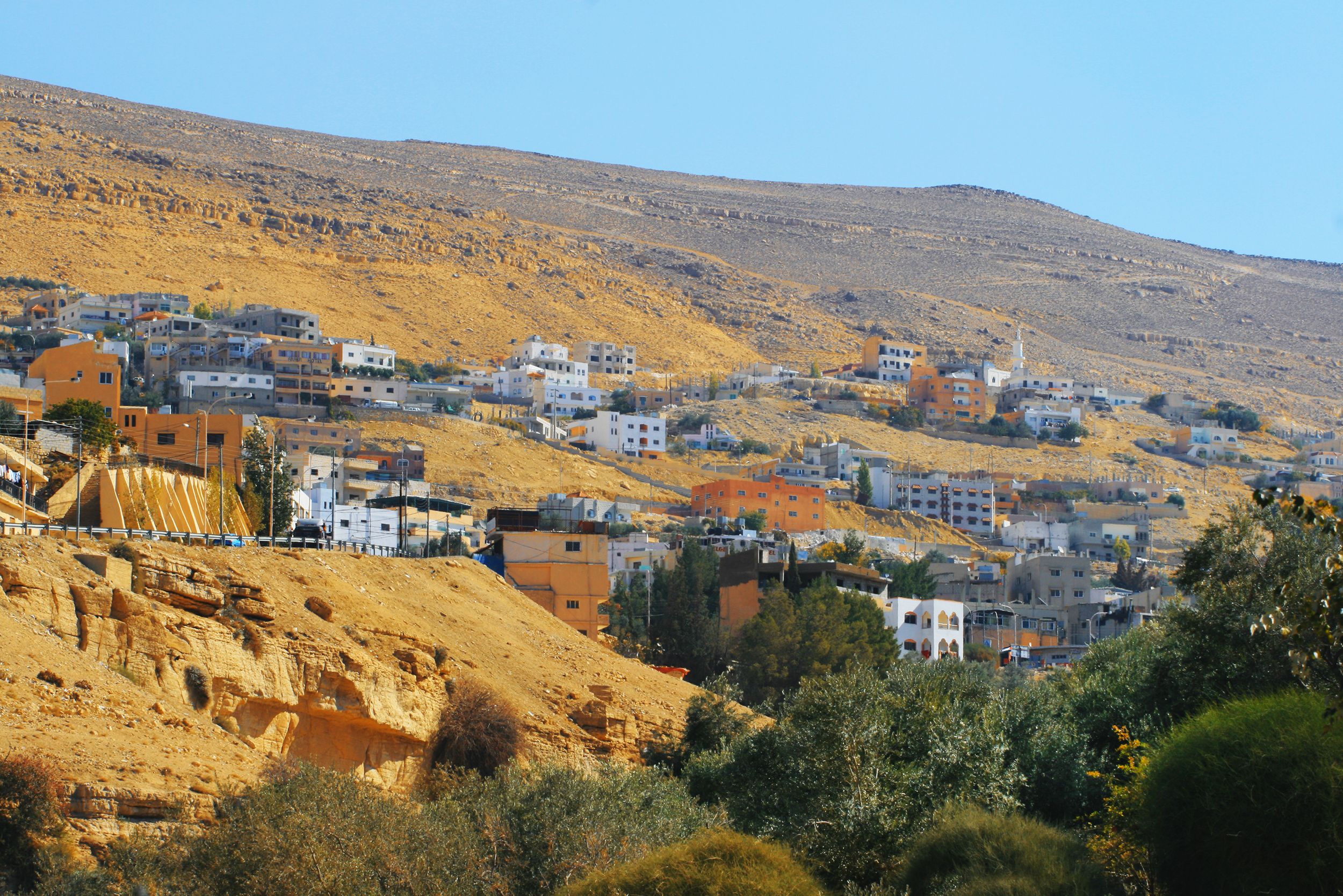 Construction vehicles and cranes work on a densely packed hillside residential development in the West Bank.