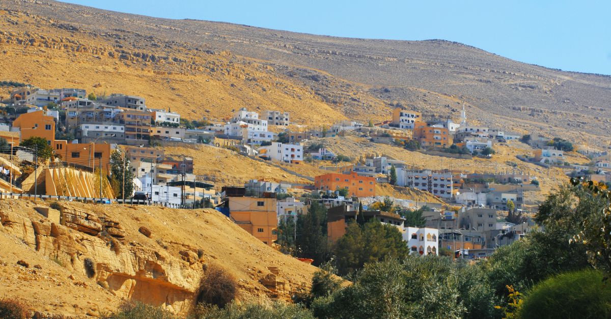 Construction vehicles and cranes work on a densely packed hillside residential development in the West Bank.