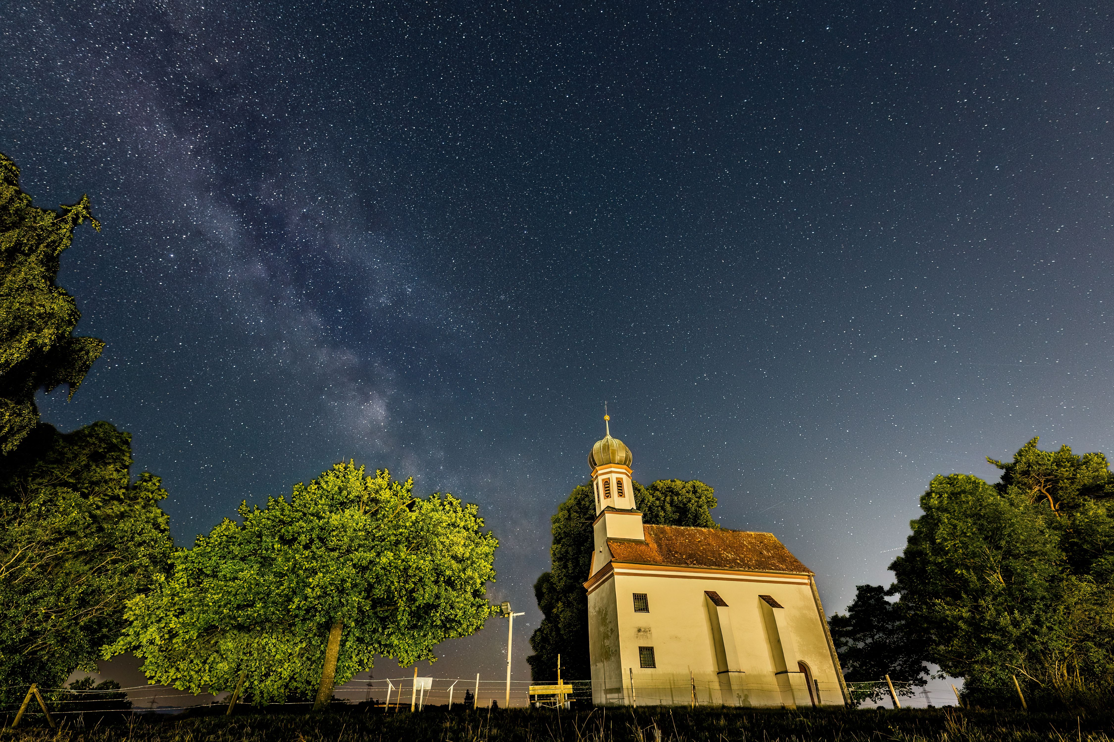 A serene night sky with a chapel in Biessenhofen, Bavaria, beneath the Milky Way.