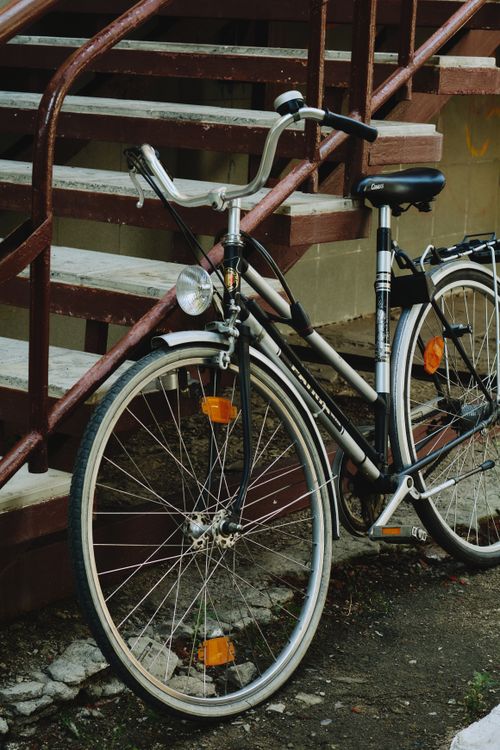 Free Classic bicycle leaning against outdoor metal staircase, urban setting. Stock Photo