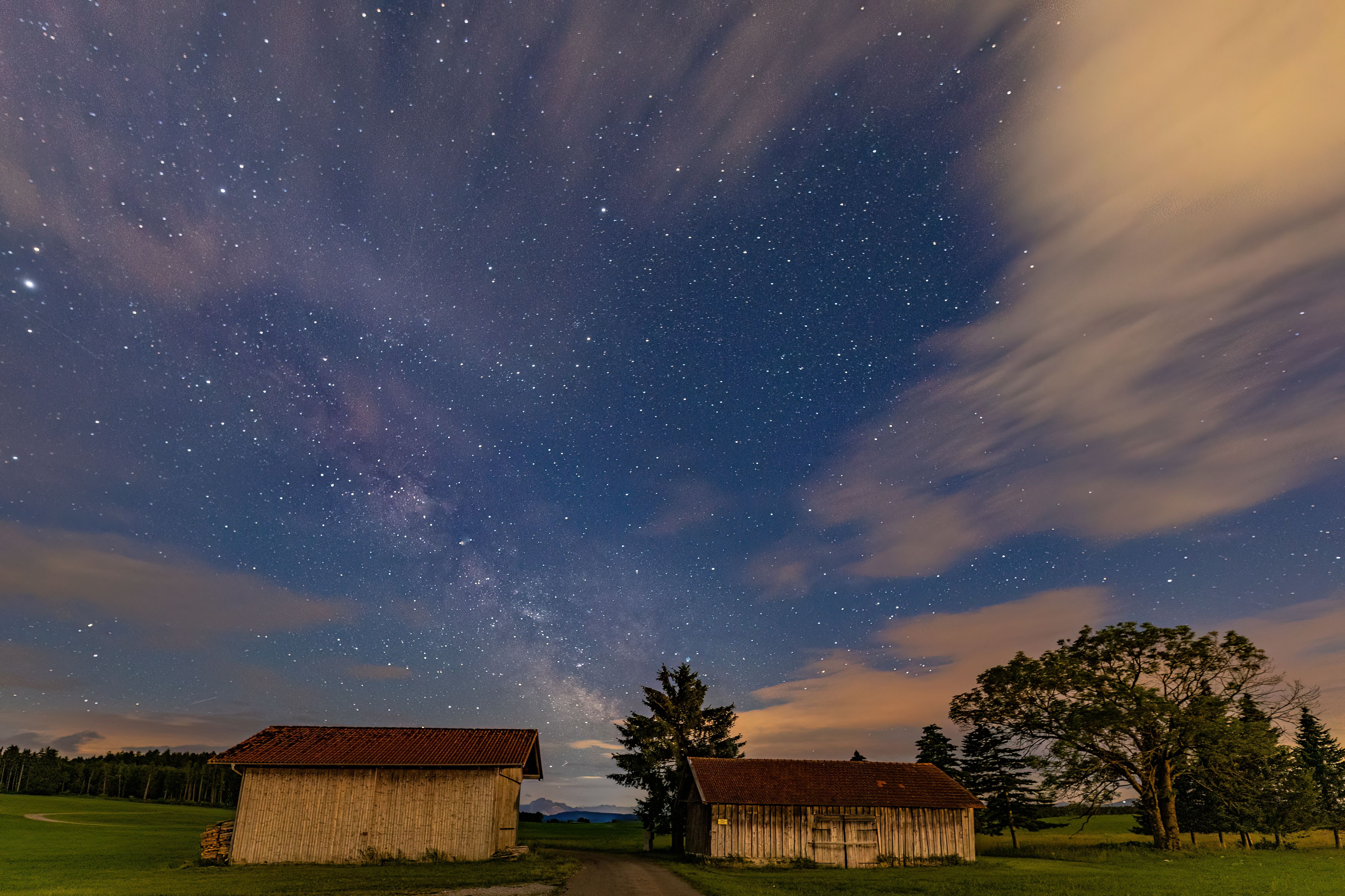 Night sky view with the Milky Way over rural huts in Marktoberdorf, Bavaria, Germany. A breathtaking celestial scene.