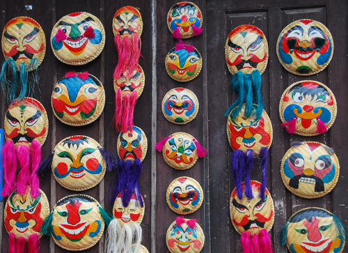 Free Vivid traditional masks with colorful designs and tassels displayed on a wooden wall. Stock Photo