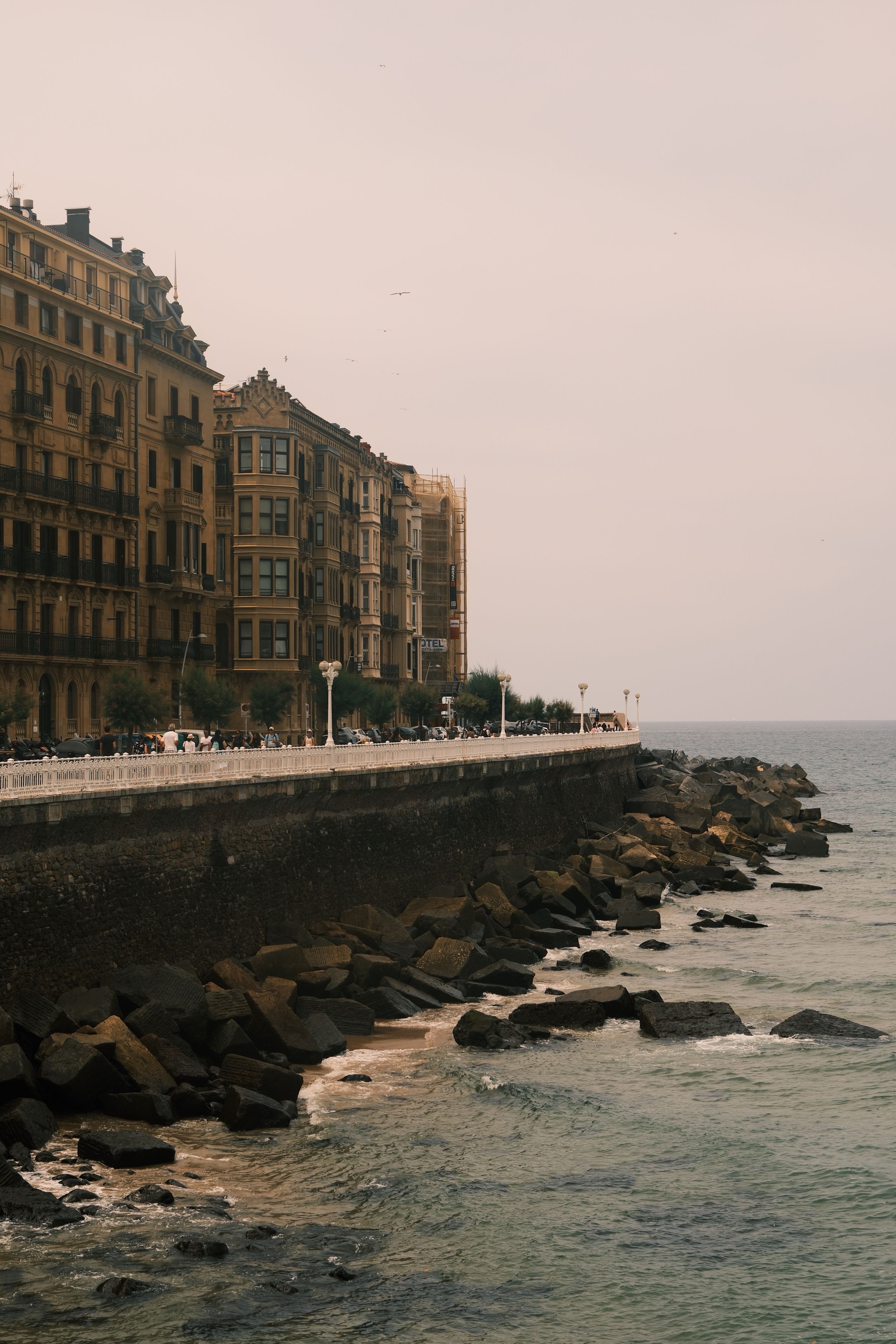 Scenic view of coastal architecture in San Sebastián, Spain, with historic buildings and ocean waves.