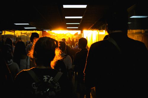Free Silhouetted people walking in a tunnel towards bright evening sunlight, creating a dramatic silhouette effect. Stock Photo