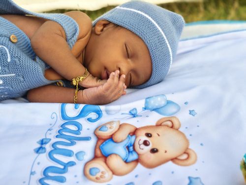Free Peaceful newborn baby sleeping on a blue blanket with cute bear design. Stock Photo