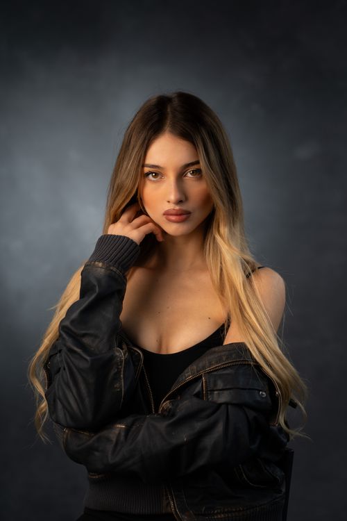Free A captivating studio portrait of a young woman wearing a denim jacket, exuding confidence and style. Stock Photo