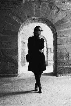 Stylish silhouette of a person standing in an ancient stone archway.
