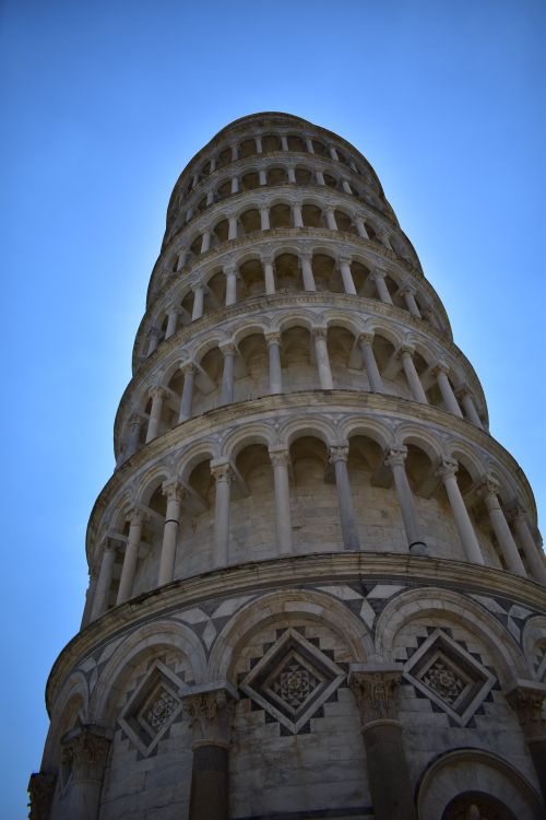 Free Dramatic low-angle view of the Leaning Tower of Pisa with clear blue sky backdrop. Stock Photo
