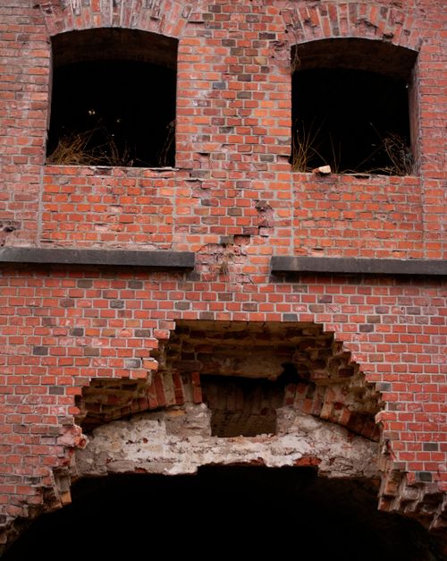 Free Close-up view of a decaying brick wall with arched windows in a historic abandoned structure. Stock Photo