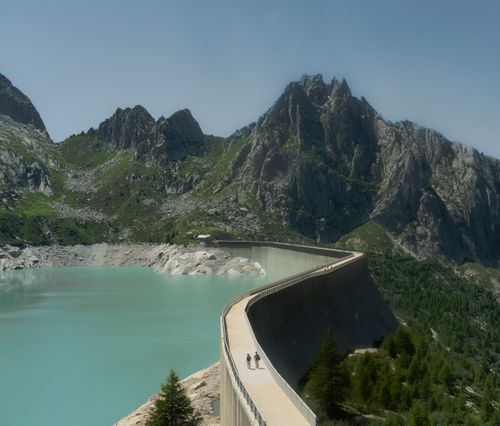 Free A breathtaking view of an alpine dam, turquoise lake, and towering mountains. Stock Photo