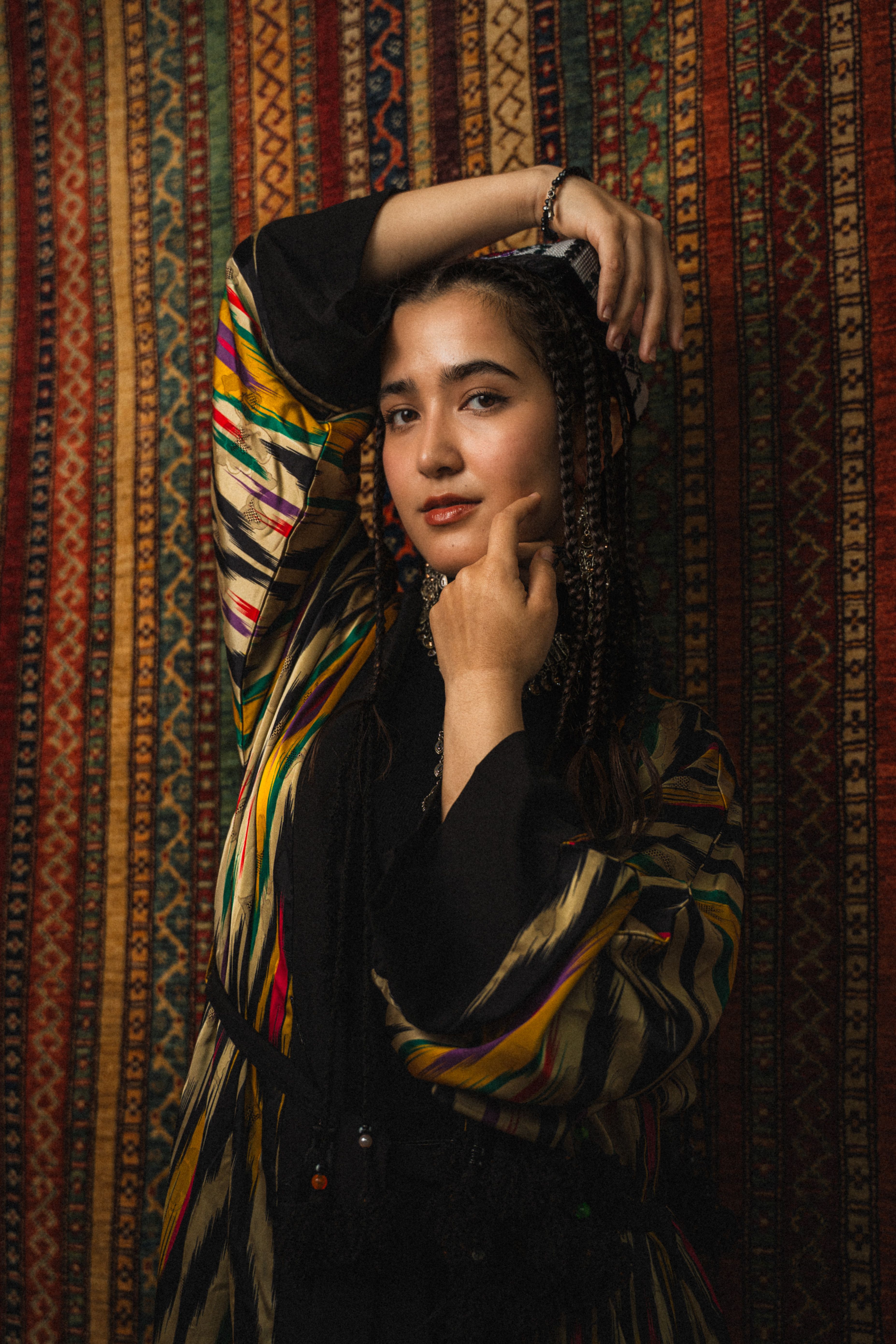 Vibrant portrait of a woman in traditional attire with woven textile backdrop.