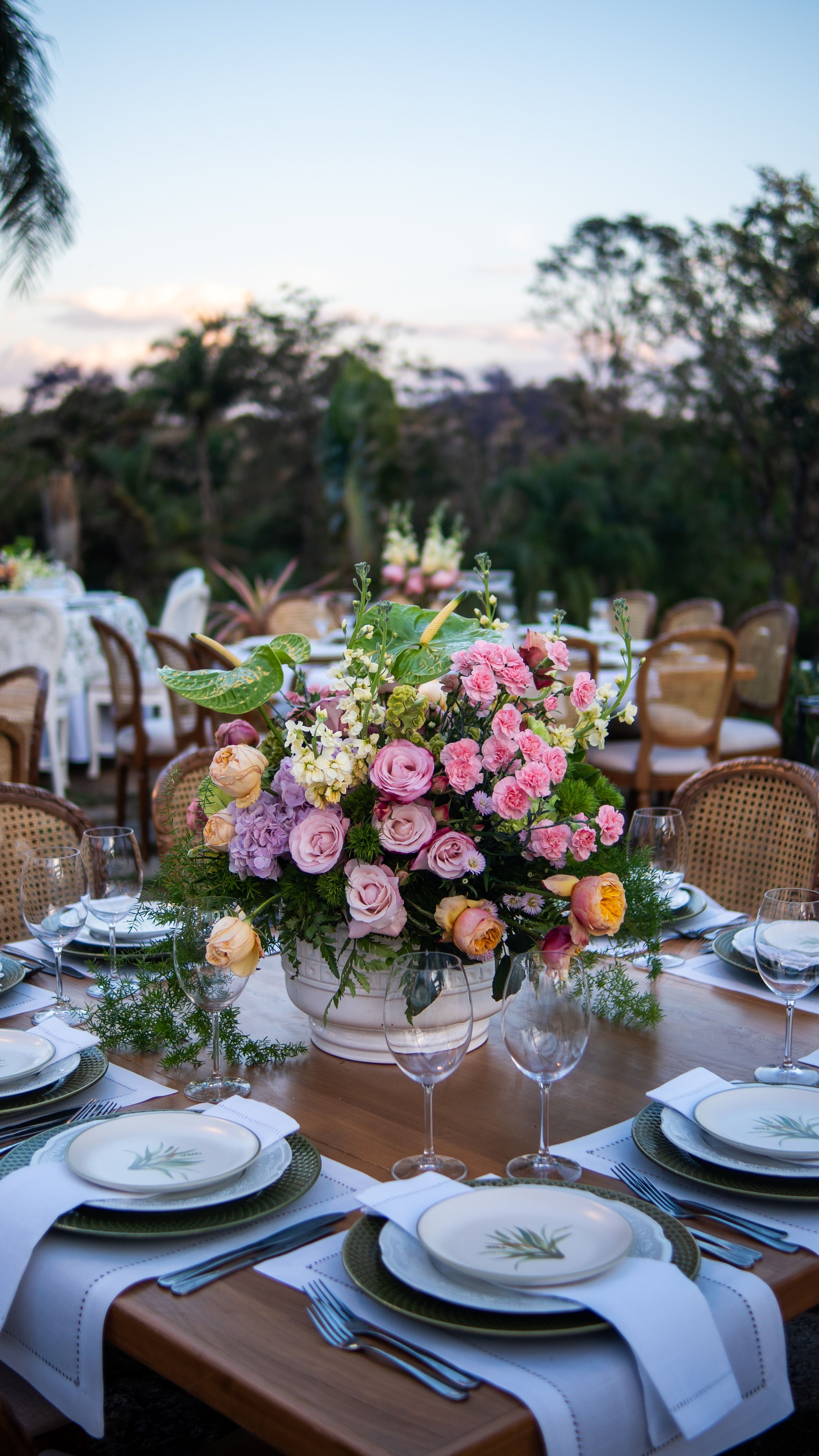Mesa de recepção de casamento ao ar livre, lindamente decorada com centro de mesa floral durante o dia.
