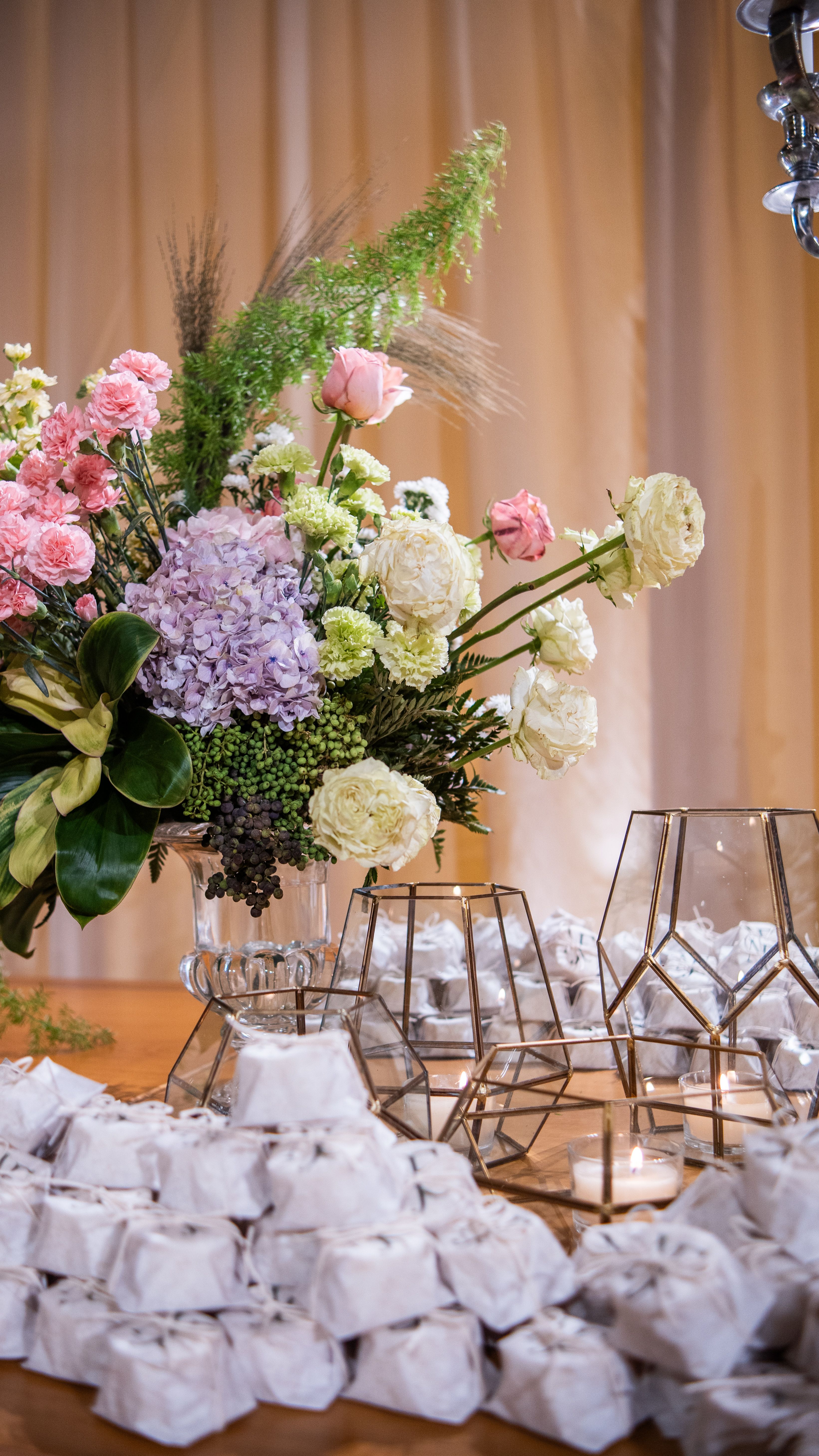 A beautiful floral centerpiece with delicately wrapped pouches on a wooden table.