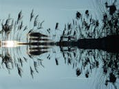 日落时分，平静的池塘上芦苇的倒影展现了大自然的宁静