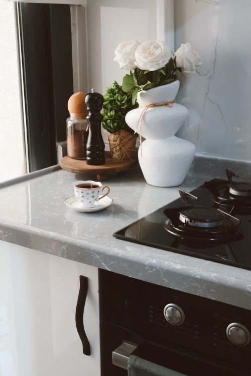 Free A modern kitchen counter with a coffee cup, vase, and spices, perfect for lifestyle themes. Stock Photo
