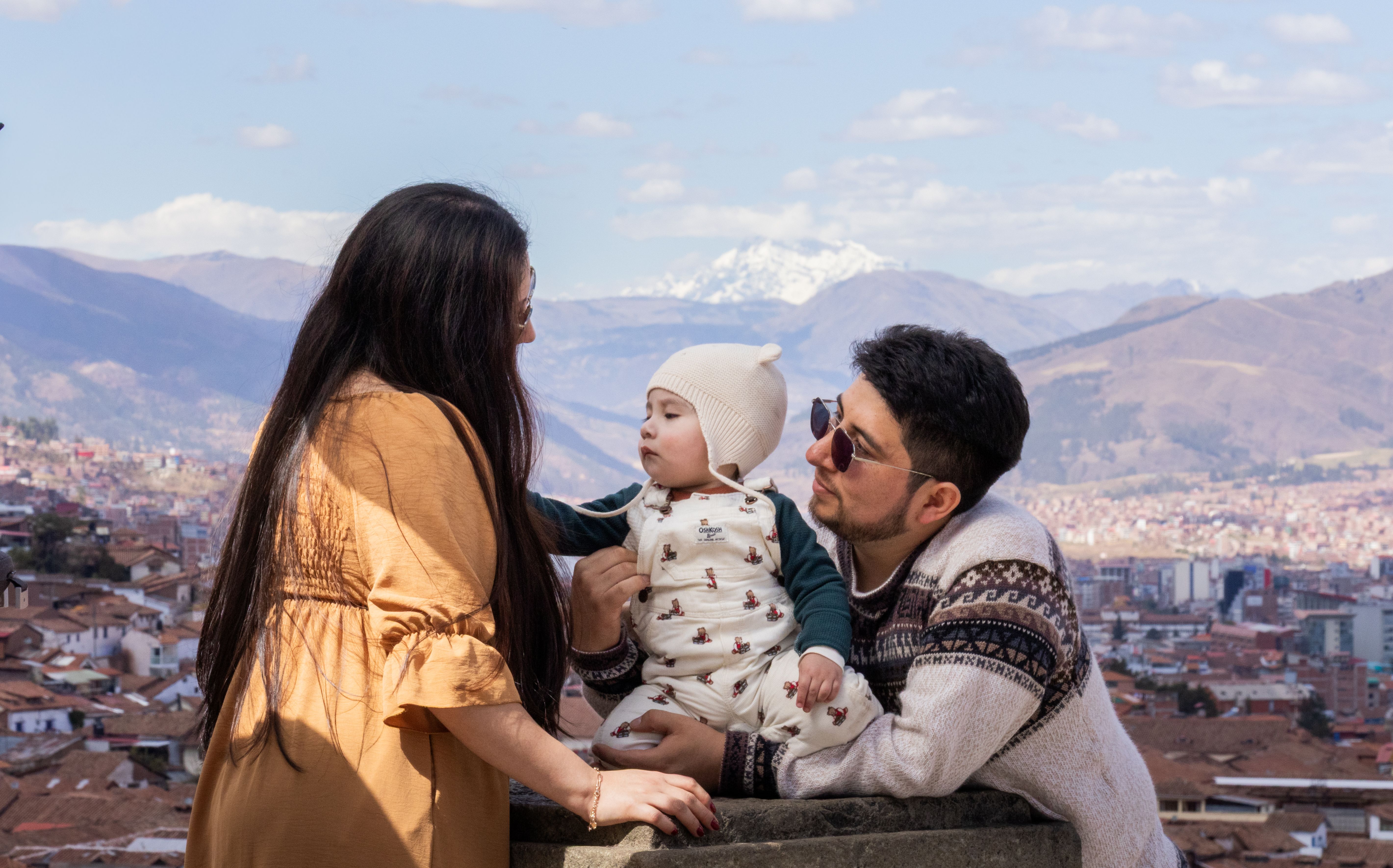 A family enjoys a scenic view of Cusco, Peru with the Andes mountains in the background.