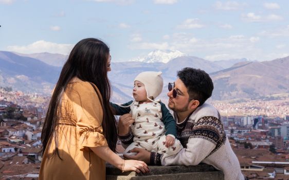 A family enjoys a scenic view of Cusco, Peru with the Andes mountains in the background.