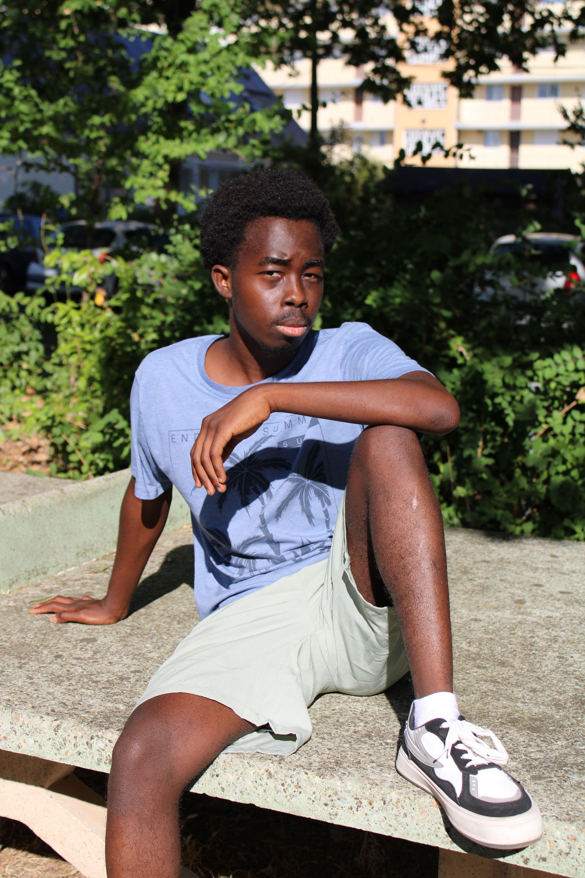 Casual young man sitting on a bench in a sunny urban park.