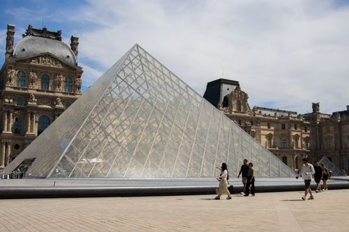 Free The iconic Louvre Pyramid beneath a blue sky in Paris, France. Stock Photo