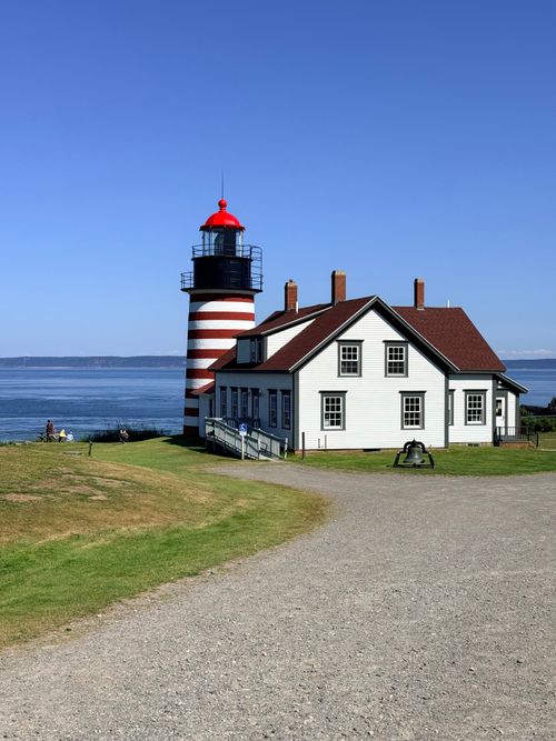 Free A clear view of the West Quoddy Head Lighthouse by the ocean under a bright blue sky. Stock Photo