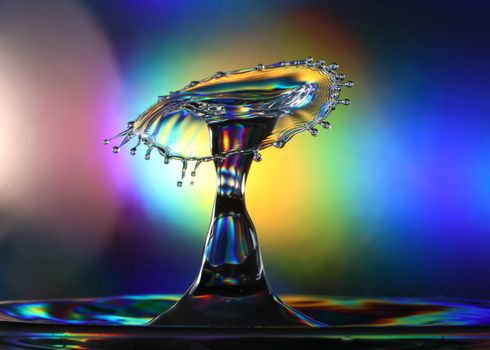 Artistic capture of a colorful water drop collision with vibrant rainbow hues.
