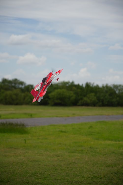 Free RC plane in mid-flight over a lush green field under a cloudy sky in Wichita Falls, Texas. Stock Photo