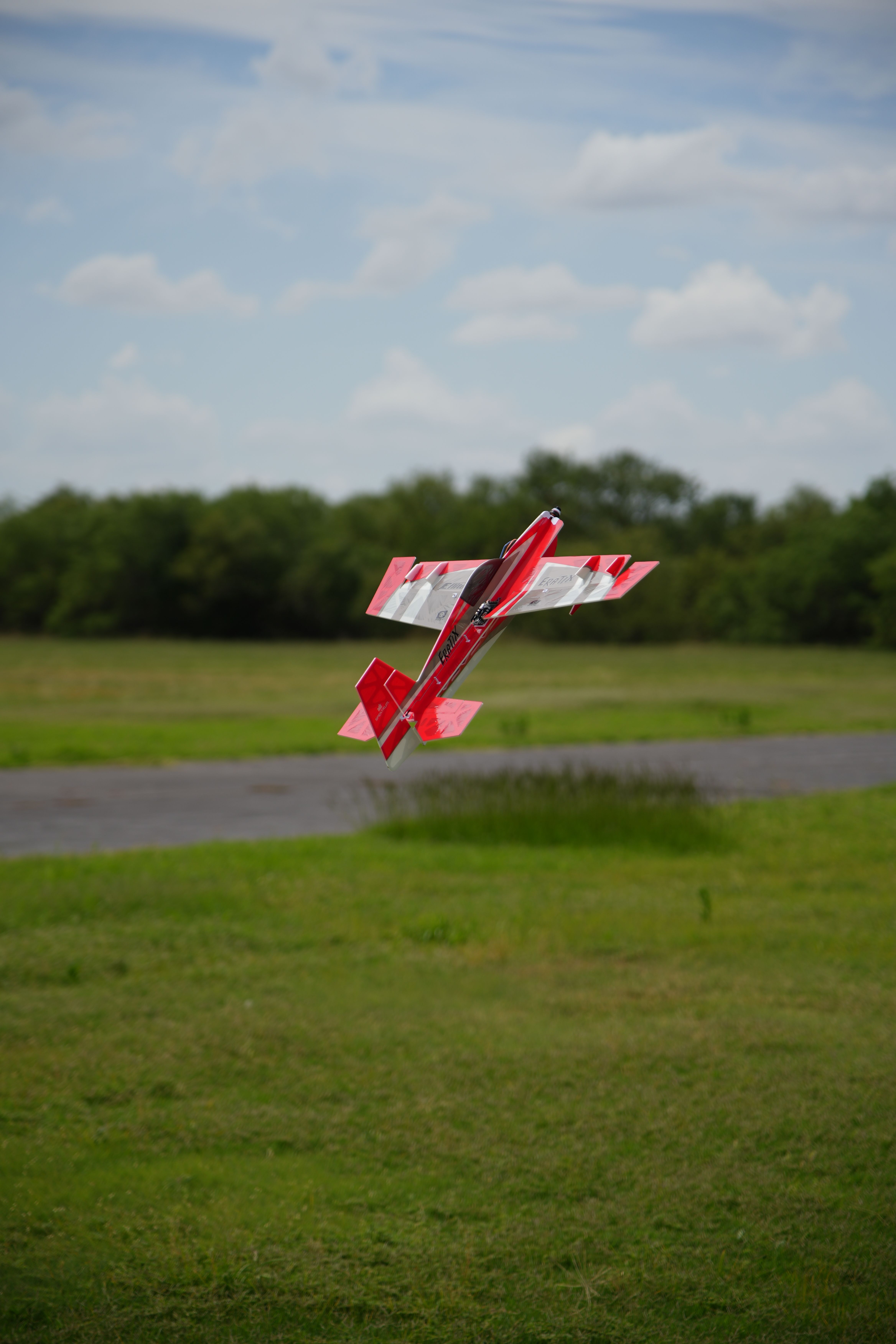 Red RC plane executing a dynamic maneuver in Wichita Falls, Texas.