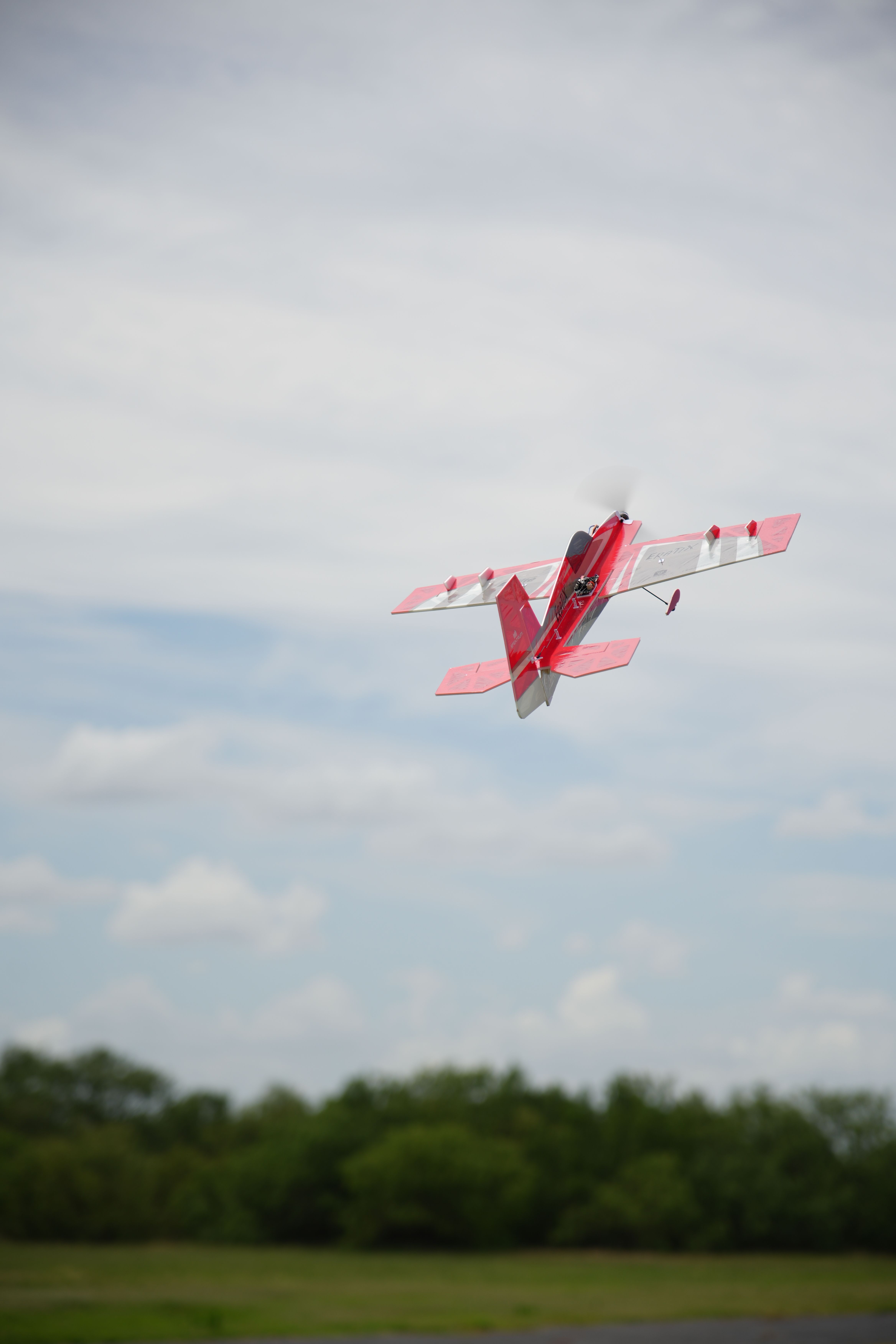 Captivating image of a red RC plane performing aerial maneuvers against a clear sky in Texas.