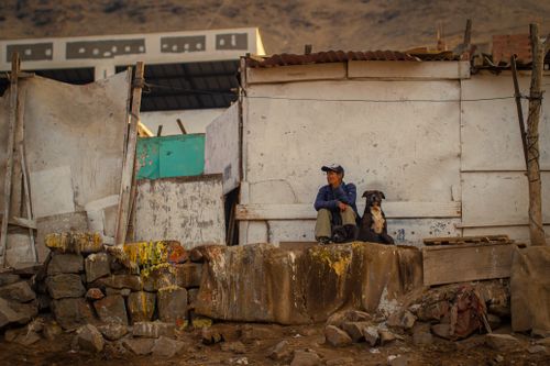 Free A man and his dog sitting outside a deteriorating building with a rustic urban backdrop. Stock Photo
