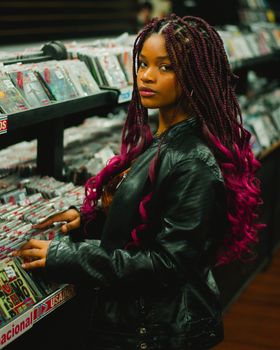 Stylish young woman with braids exploring records in a vintage music store.
