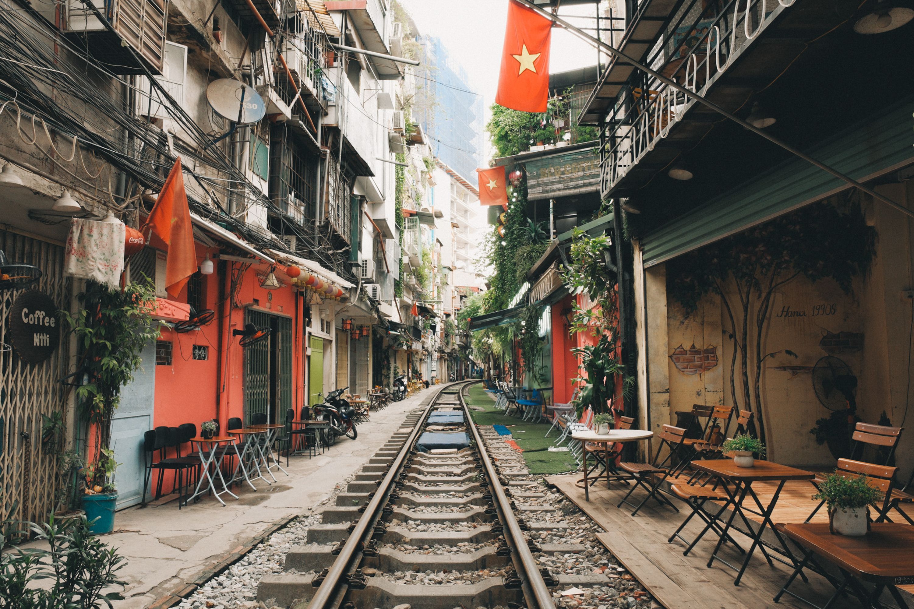 Capture of Hanoi's famous Train Street lined with cafes and shops, vibrant urban life.