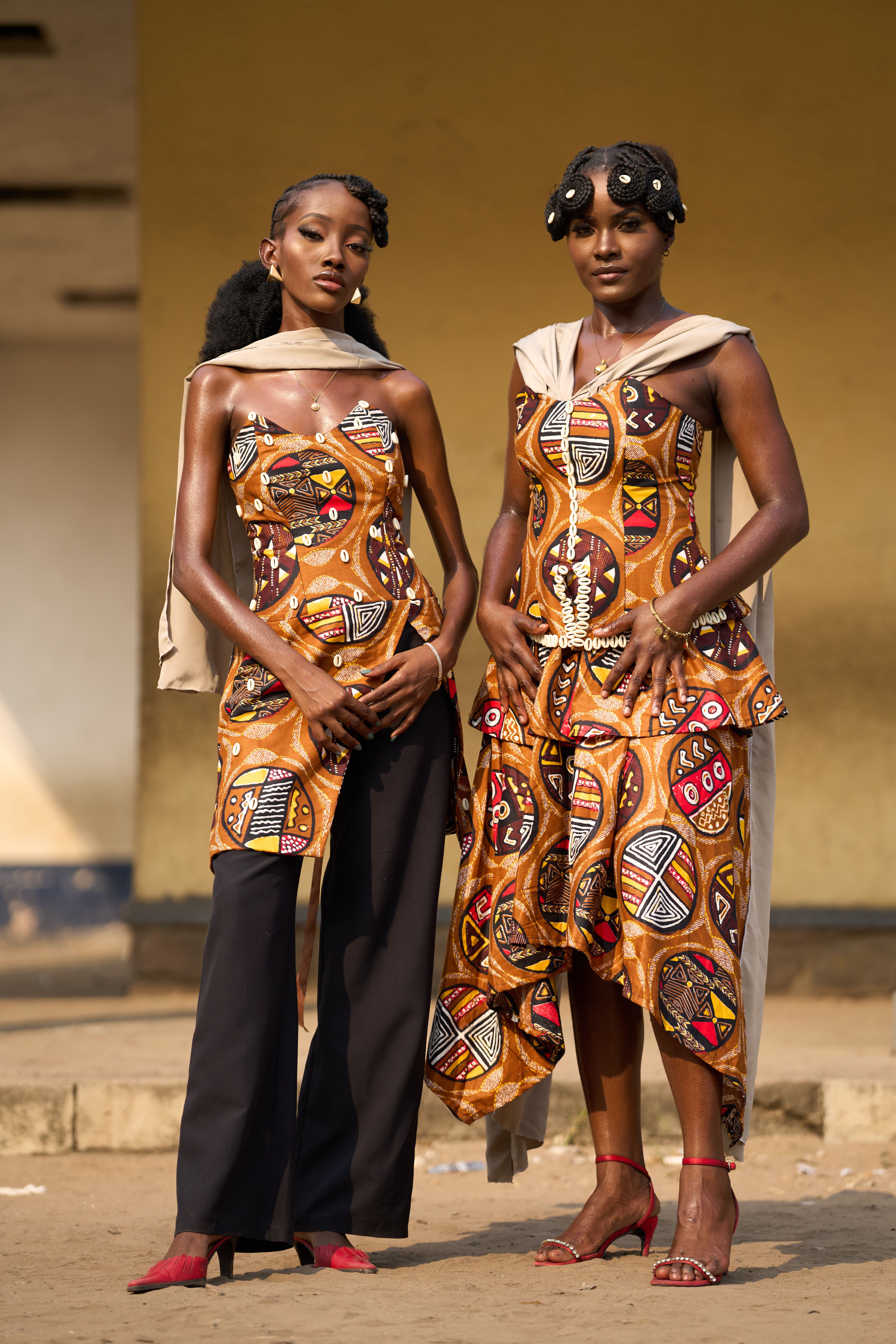 Two women in traditional African prints showcase modern style in Kinshasa.