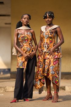 Two women in traditional African prints showcase modern style in Kinshasa.