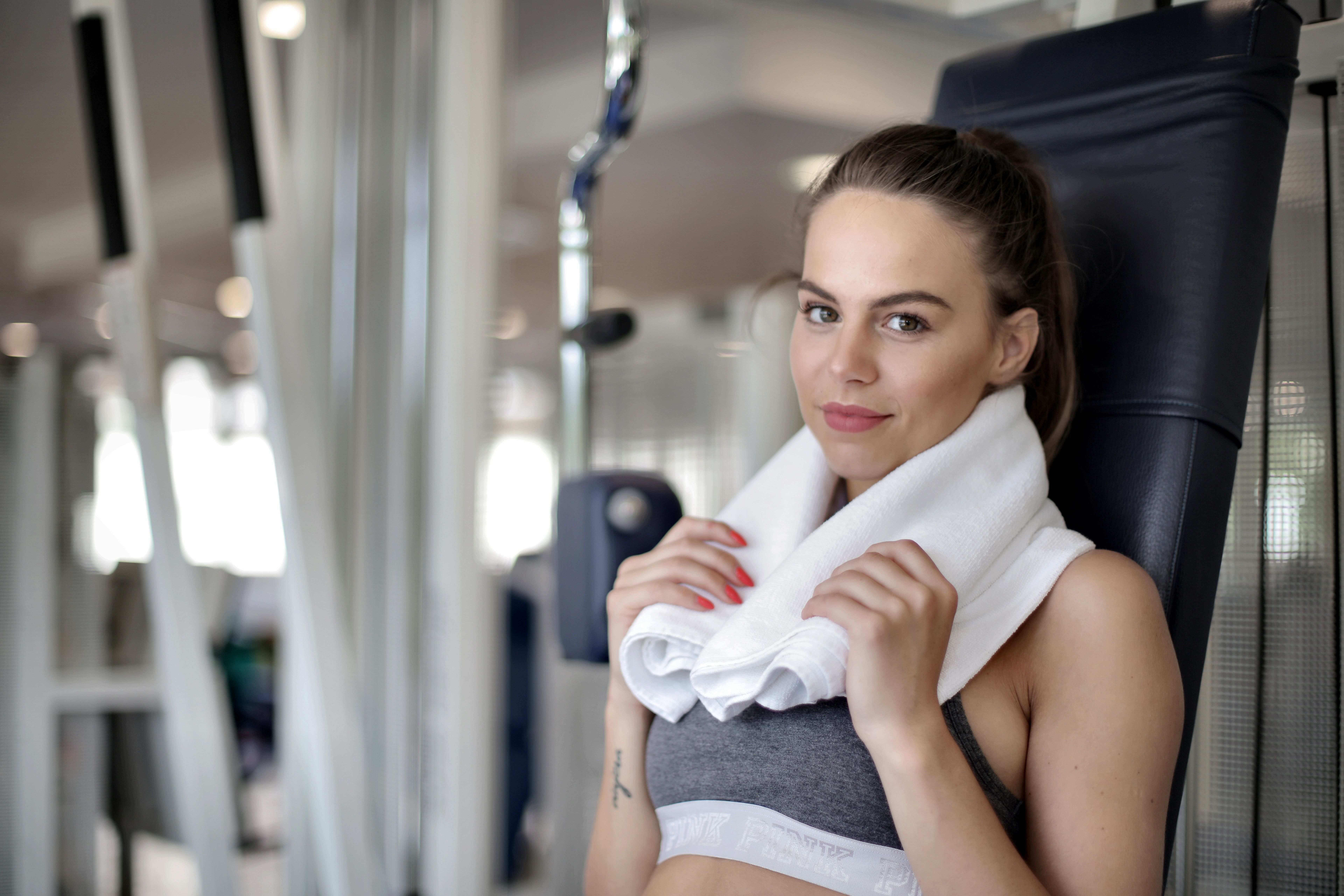 A young woman relaxing with a towel in a fitness gym, looking confident.