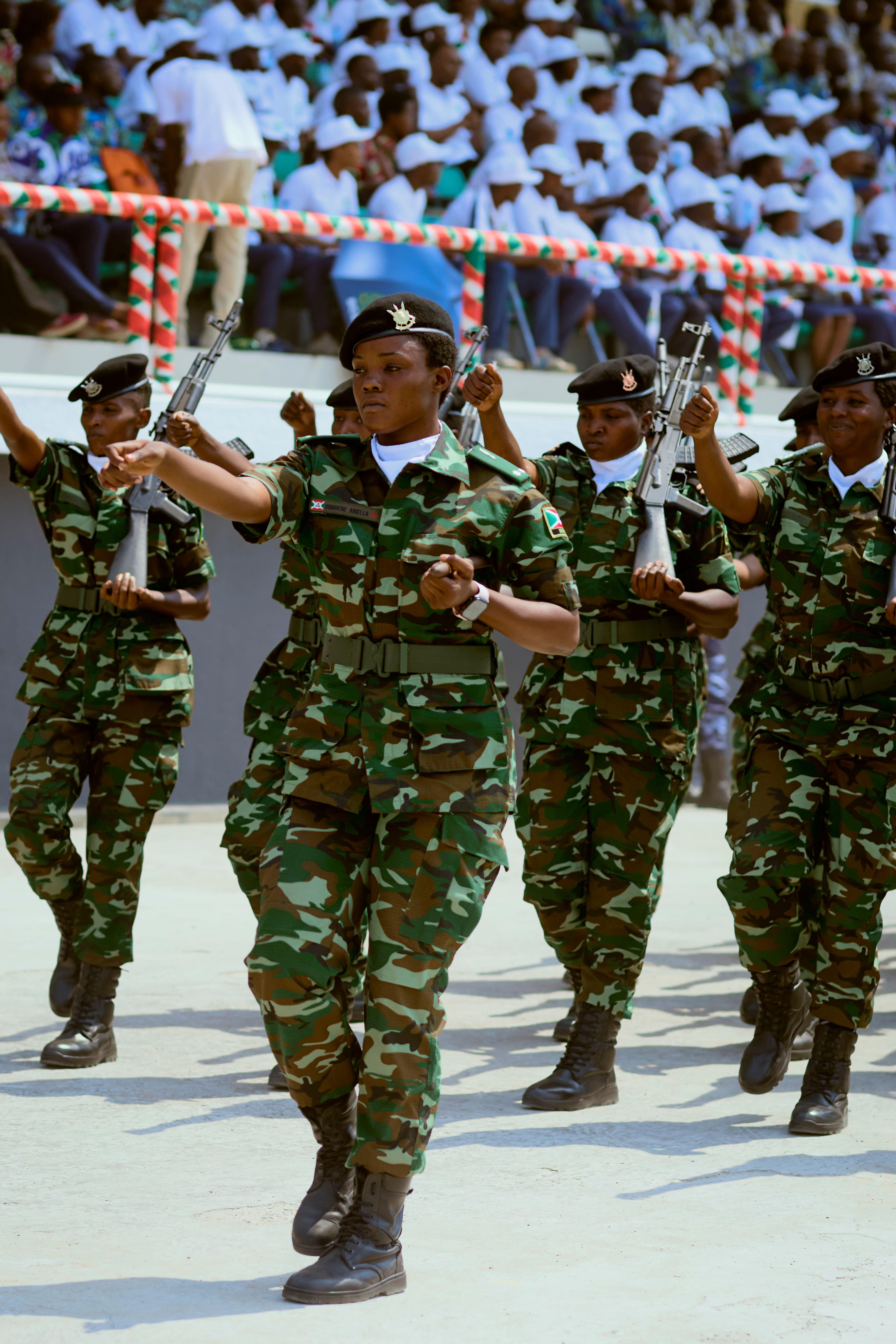 Group of soldiers in uniform performing a synchronized march in a public event.